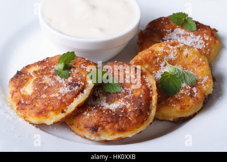 Pfannkuchen mit Käse auf einem weißen Teller mit Sauerrahm Closeup. eine Draufsicht auf eine horizontale Stockfoto