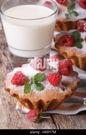 Leckere Himbeer Muffins Closeup und Milch in ein Glas auf einem Holztisch vertikale Stockfoto