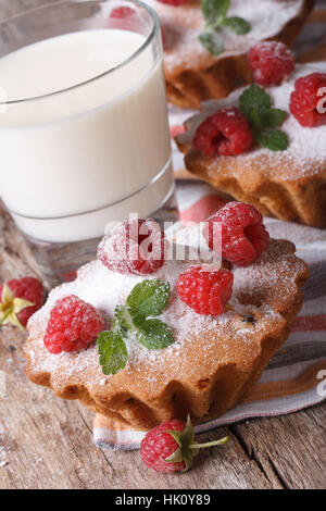 frische Muffins mit Himbeeren Closeup und Milch in ein Glas auf einem Holztisch vertikale Stockfoto