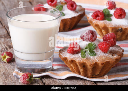 frische Muffins mit Himbeeren Closeup und Milch in ein Glas auf einem Holztisch horizontale Stockfoto
