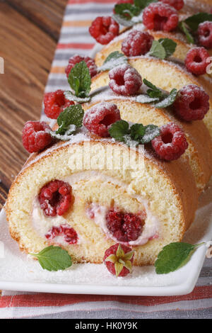 Biskuitrolle mit Himbeeren und Minze hautnah auf dem Tisch. vertikale Stockfoto