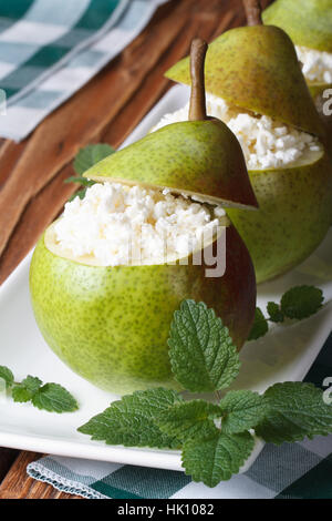 reife Birnen gefüllt mit Hüttenkäse auf weißen Teller Closeup auf vertikale Tabelle Stockfoto