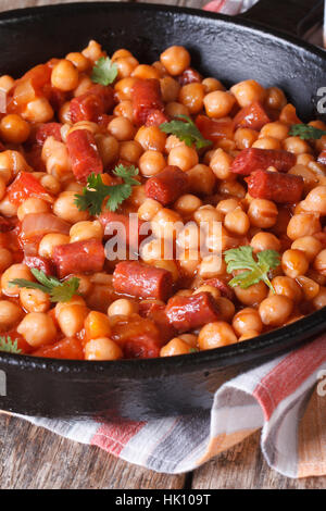 Kichererbsen mit Chorizo in einer Pfanne Nahaufnahme und mit den Zutaten auf der horizontalen Tischplatte anzeigen Stockfoto