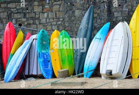 Kajaks, Kanus und Boote aufgereiht gegen das Meer Wand an der hübschen Fischerdorf Mousehole an der südlichen Küste von Cornwall, England, Großbritannien Stockfoto