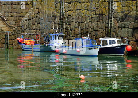 Kleine Fischerboote vertäut gegen die Hafenmauer im malerischen Fischerdorf Mousehole an der südlichen Küste von Cornwall, England, Großbritannien Stockfoto