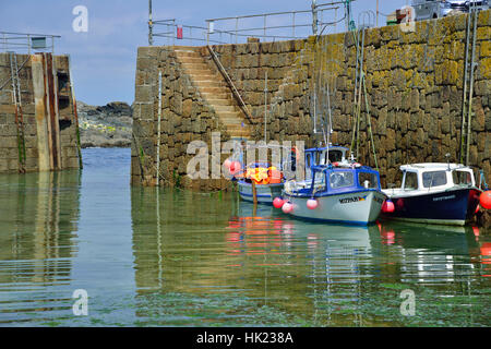 Kleine Fischerboote vertäut gegen die Hafenmauer im malerischen Fischerdorf Mousehole an der südlichen Küste von Cornwall, England, Großbritannien Stockfoto