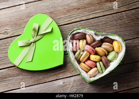 Bunte Macarons in Valentinstag Herz geformte Geschenkbox auf Holztisch. Ansicht von oben Stockfoto