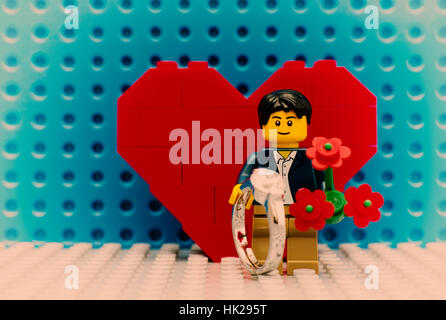 Tambow, Russische Föderation - 3. September 2015 Lego Mann Minifigur mit Ring und roten Blumen stehen im Vordergrund des Herzens auf Lego Grundplatten. Stockfoto