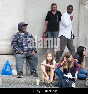 LONDON, ENGLAND - 12. Juli 2016 bunte Menge sitzt auf dem Bürgersteig für Rest Stockfoto