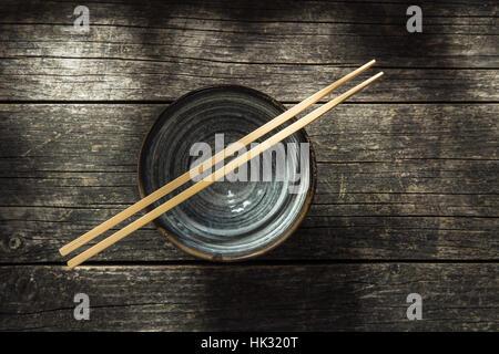 Asiatische Schale und Stäbchen auf alten Tisch. Ansicht von oben. Stockfoto