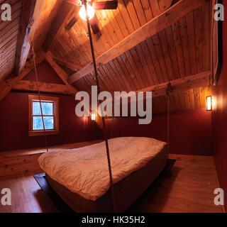 Attic Loft-Schlafzimmer mit einem Bett hängen in einem kanadischen Timber Frame Landhaus, Interieur mit viel Holz, Muskoka, Ontario, Kanada Stockfoto