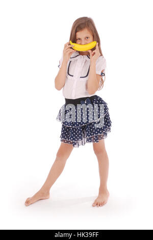 Ein junges Mädchen hält eine Banane in den Mund, ein Lächeln zu imitieren. Isoliert auf weißem Hintergrund Stockfoto