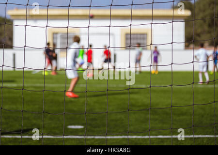 Kinder Fußball spielen auf einem synthetischen Feld, Schuß von der Rückseite Stockfoto