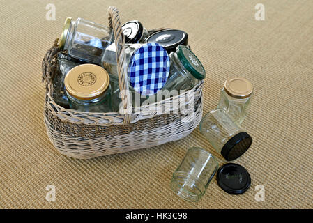 Leere Gläser in Vintage Weidenkorb mit einigen gefallen auf Boden, für die Wiederverwendung in Marmelade machen oder recycling Stockfoto