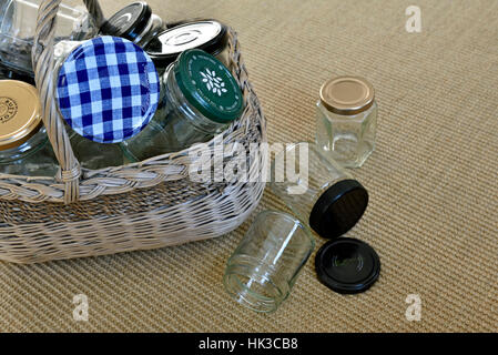 Leere Gläser in Vintage Weidenkorb mit einigen gefallen auf Boden, für die Wiederverwendung in Marmelade machen oder recycling Stockfoto