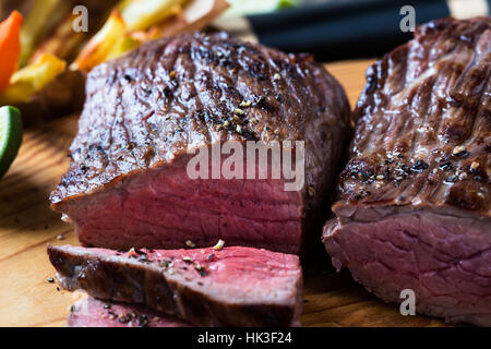 Seltene gebratenes Rindsfilet mit Pommes-Frites auf Schneidebrett Stockfoto