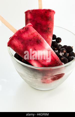 Hausgemachtes Joghurt Eis knallt mit frischen schwarzen Beeren für heiße Sommertage auf einem weißen Tisch Stockfoto