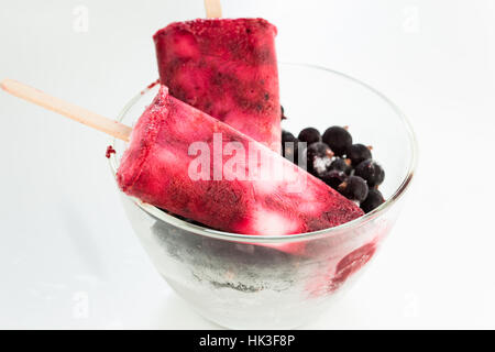Hausgemachtes Joghurt Eis knallt mit frischen schwarzen Beeren für heiße Sommertage auf einem weißen Tisch Stockfoto