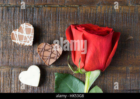 Leuchtend rote Rose und drei Herz-geformte Schokolade Stockfoto