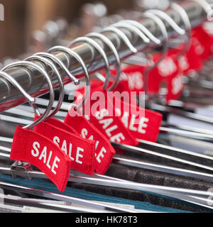 roten Aufkleber mit dem Wort Verkauf auf Kleiderbügel außerhalb Mode speichern Stockfoto