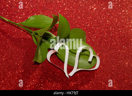Zwei weiße Papierherzen aus Papier mit grüne Blume rot leuchtenden Hintergrund Stockfoto