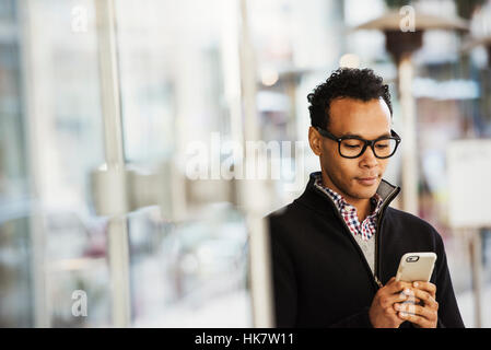 Ein junger Mann auf einem Handy halten und Lächeln. Stockfoto