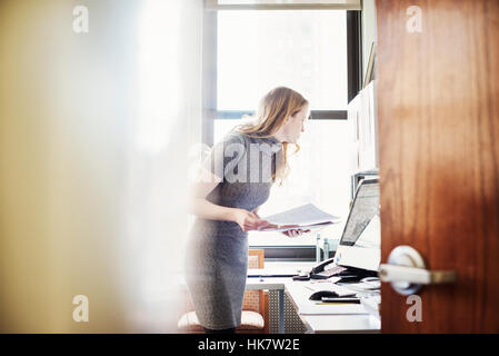 Eine Frau in einem Büro, durch eine offene Tür zu sehen. Stockfoto