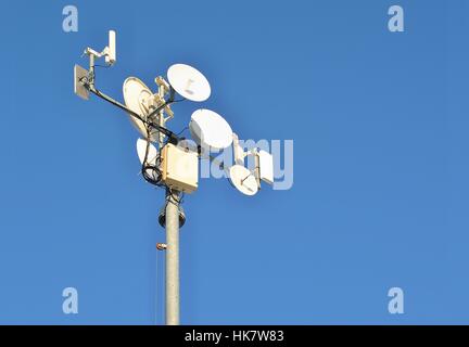 Antenne-Pylon mit Sender und Satelliten auf blauen Himmelshintergrund. Stockfoto