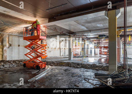 Schweißer auf Scissor Lift auf Baustelle Stockfoto