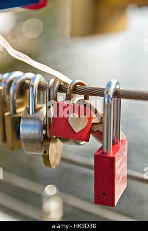 Ein Detail aus der Nähe von Liebesschlössern, die an einem Metallfaden an einer Brücke in Melbourne hängen Stockfoto