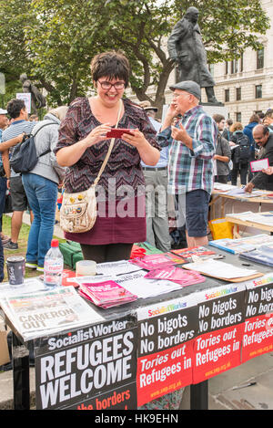 Jeremy Corbyn Anhänger hinter einem Stall überprüft ihr Telefon mit Winston Churchills Statut hinter ihr in Parliament Square, London. Stockfoto