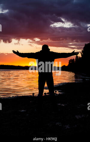 Silhouette der Mann heben seine Hände oder offene Arme wenn aufgehenden Sonne Stockfoto