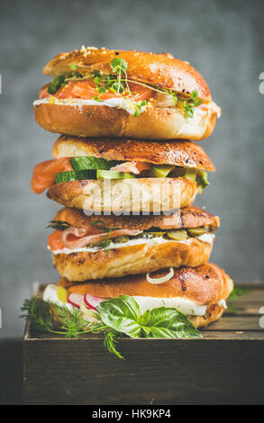 Haufen von Bagels mit Lachs, Eiern, Gemüse, Kapern und Frischkäse, grauer Beton Hintergrund. Gesundes Frühstück, Mittagessen oder Take-away-Food-Konzept Stockfoto