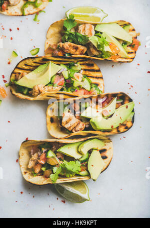 Gesund Mais-Tortillas mit gegrilltem Hähnchen Filet, Avocado, frischer Salsa, Limetten über Licht grau Marmor Hintergrund, Ansicht von oben. Gesundes Essen, glutenfrei Stockfoto