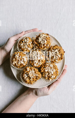 Eine Frau hält einen Teller voller frisch gebackene Süßkartoffel-Muffins aus der Ansicht von oben fotografiert. Stockfoto