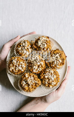 Eine Frau hält einen Teller voller frisch gebackene Süßkartoffel-Muffins aus der Ansicht von oben fotografiert. Stockfoto