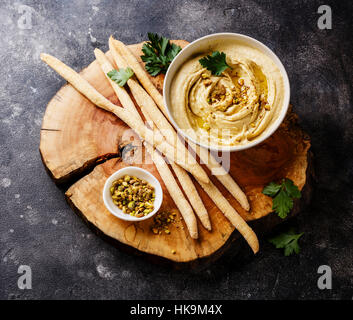 Hausgemachter Hummus mit Pistazien und Brot klebt auf schwarzem Stein Stockfoto