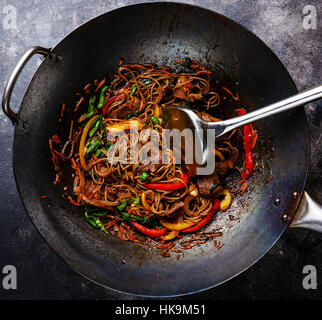 Unter Rühren braten Nudeln Soba mit Rindfleisch und Gemüse im Wok-Pfanne auf dunklem Hintergrund hautnah Stockfoto