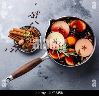 Glühwein Wein Heißgetränk mit Zitrus, Apfel und Gewürzen in Aluminium Kasserolle auf konkrete Hintergrund Stockfoto