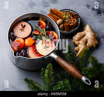 Glühwein Wein Heißgetränk mit Zitrus, Apfel und Gewürzen in Aluminium Kasserolle auf konkrete Hintergrund Stockfoto