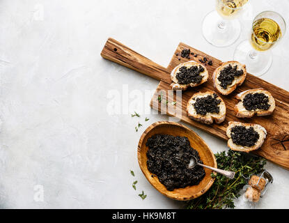 Schwarz von Störkaviar in Holzschale, Sandwiches und Champagner auf weißem Hintergrund Textfreiraum Stockfoto