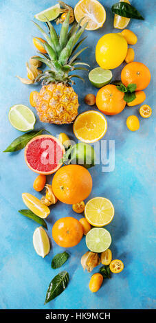 Vielzahl von ganze und geschnittene Zitrusfrüchte Ananas, Grapefruit, Zitrone, Limette, Kumquat, Clementine und Physalis mit Minze über blauen hölzernen Hintergrund. Stockfoto