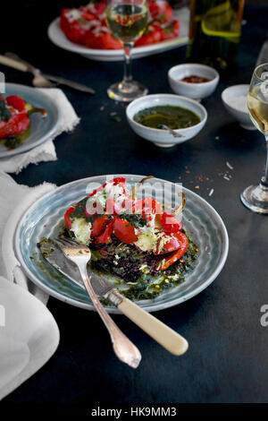 Schwarzer Reis Caprese gefüllt geröstete Paprika serviert mit frischem Basilikum-Öl und Weißwein.  Fotografiert von Vorderansicht auf einem dunkelblauen Hintergrund. Stockfoto