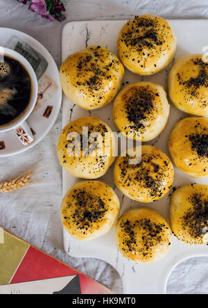 Türkische Brötchen gefüllt mit Feta und Petersilie auf einem Brett serviert, begleitet von einer Tasse Kaffee. Stockfoto