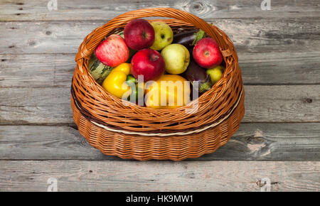 Buntes Gemüse und Äpfel im Korb auf alten Holztisch Stockfoto