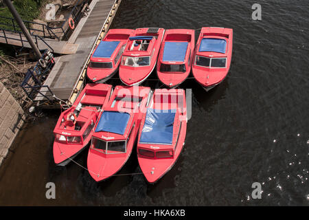 Sieben rote Boote aufgereiht bereit zu mieten auf dem Fluss Ouse in der Stadt von York in North Yorkshire Stockfoto