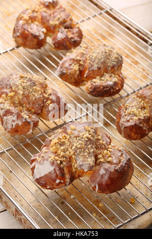 Frische Croissants aus dem Ofen und mit Zuckerglasur und Nüssen verziert Stockfoto