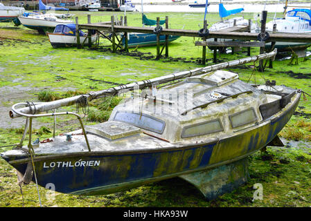 Vernachlässigt kleine Segelyacht in der Notwendigkeit der Reinigung auf dem Vorland bei Dell Quay, Chichester Harbour, West Sussex, England, Großbritannien Stockfoto