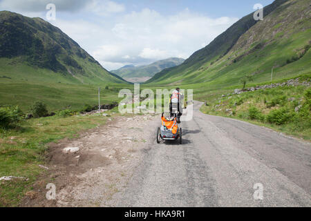 Mann, Radfahren auf der Straße neben dem Fluß Etive in Glen Etive im Hochland, Schottland. Stockfoto