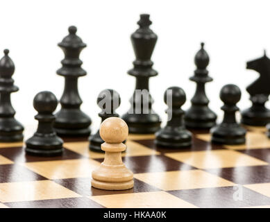 Weiße Bauern gegen eine Übermacht der schwarzen Figuren auf einem Schachbrett. Selektiven Fokus. Stockfoto